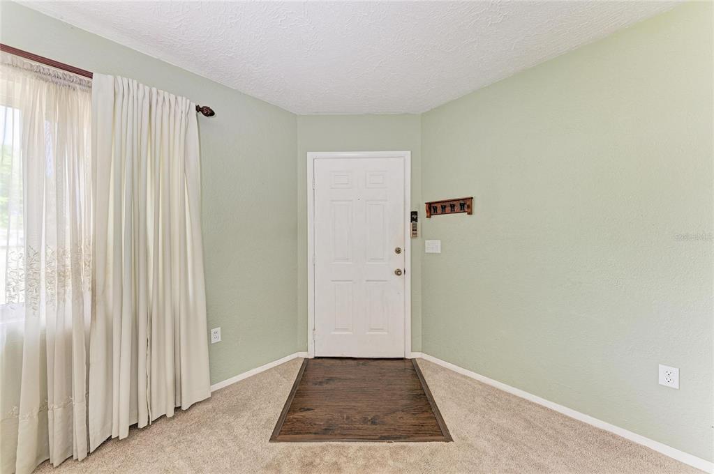 An entryway with light green walls, beige carpet, a white door, and white curtains — 2811 33RD AVENUE W, BRADENTON, FL