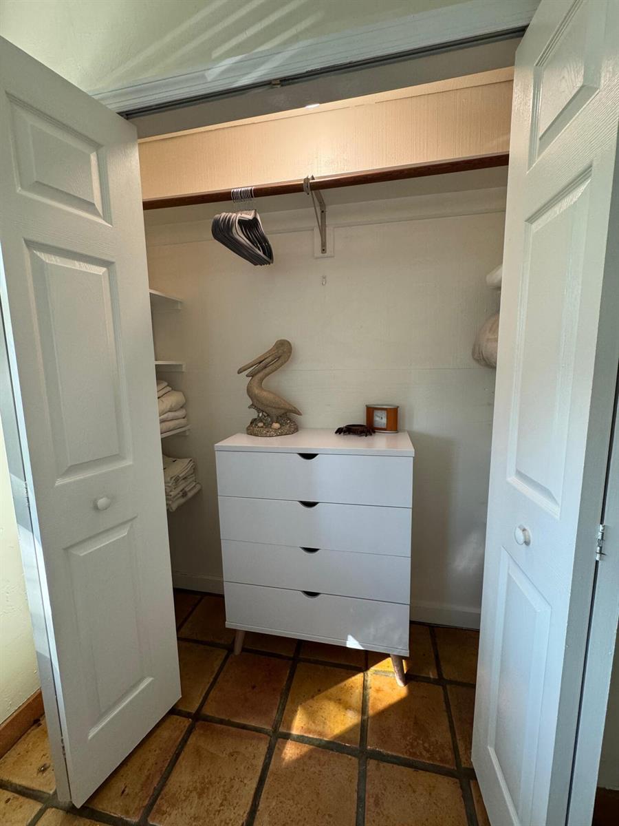 A closet with white double doors, a four-drawer dresser, shelving, and tile flooring — 256 E 24th Street, Riviera Beach FL 33404, RIVIERA BEACH, FL