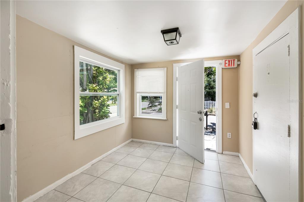 A sunroom with beige walls, tiled floors, two windows, and an open exterior door — 418 E AMELIA AVENUE UNIT A, TAMPA, FL