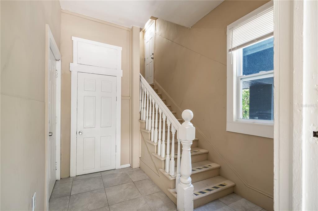 An interior view shows a tiled entryway with a staircase, white doors, and a window — 418 E AMELIA AVENUE UNIT A, TAMPA, FL