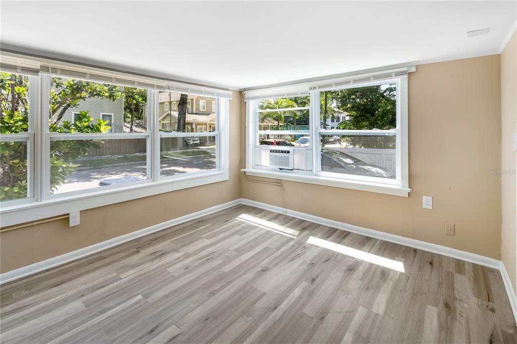 A sunroom with light wood-look flooring, tan walls, and multiple windows with an air conditioner — 418 E AMELIA AVENUE UNIT A, TAMPA, FL