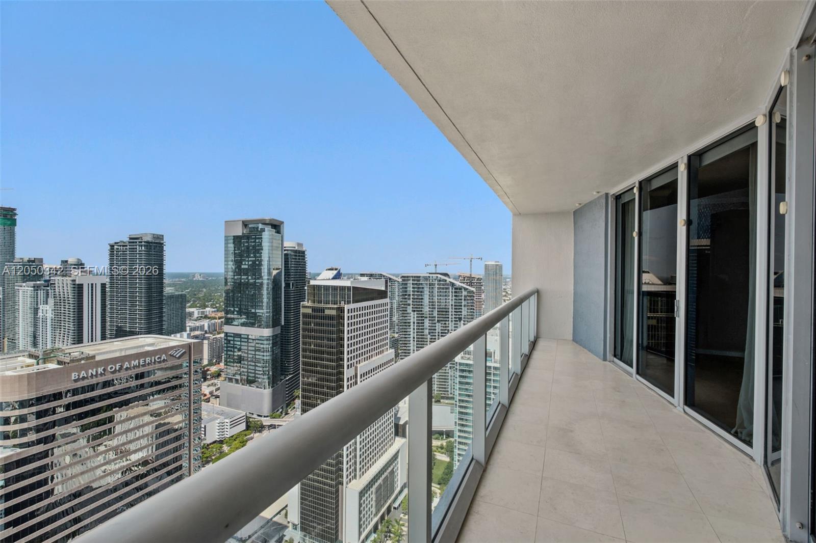 A high-rise balcony with a glass railing overlooks a dense city skyline — 495 Brickell Ave # 5309, Miami FL 33131, MIAMI, FL