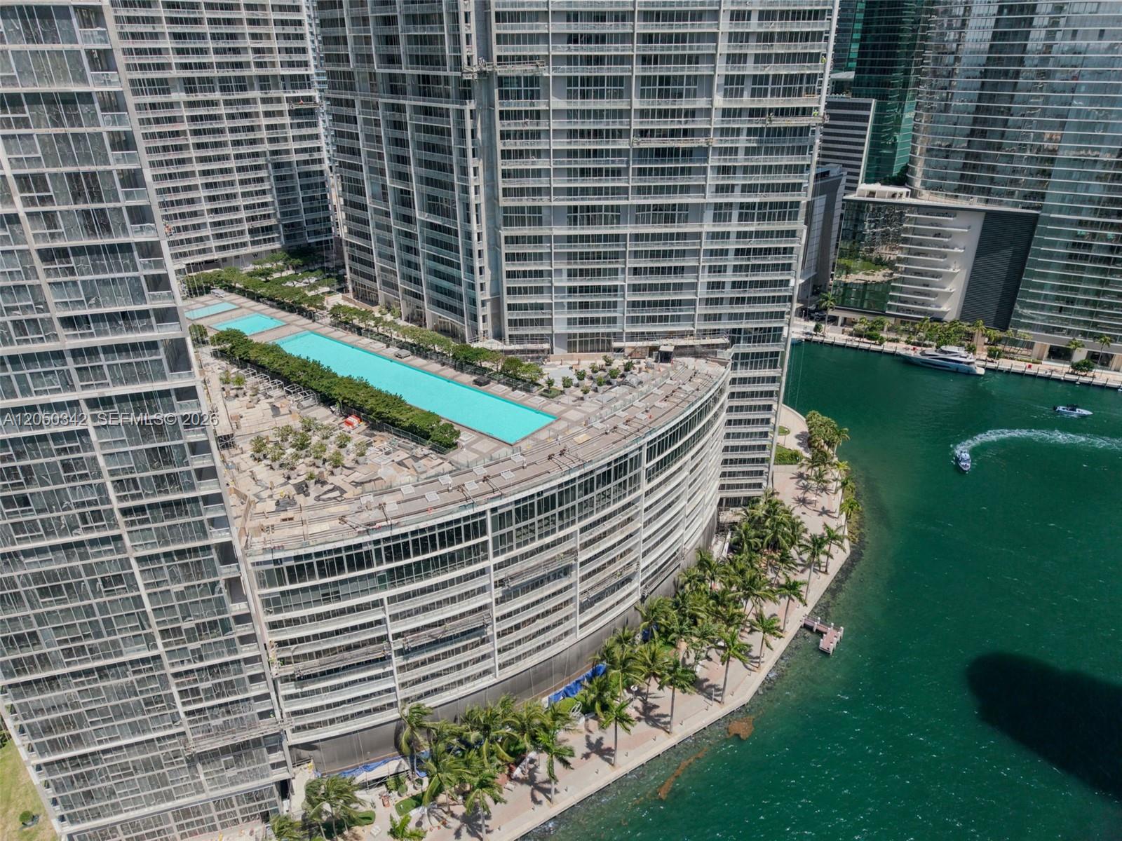 An aerial view shows a high-rise building with a large rooftop pool and waterfront promenade — 495 Brickell Ave # 5309, Miami FL 33131, MIAMI, FL