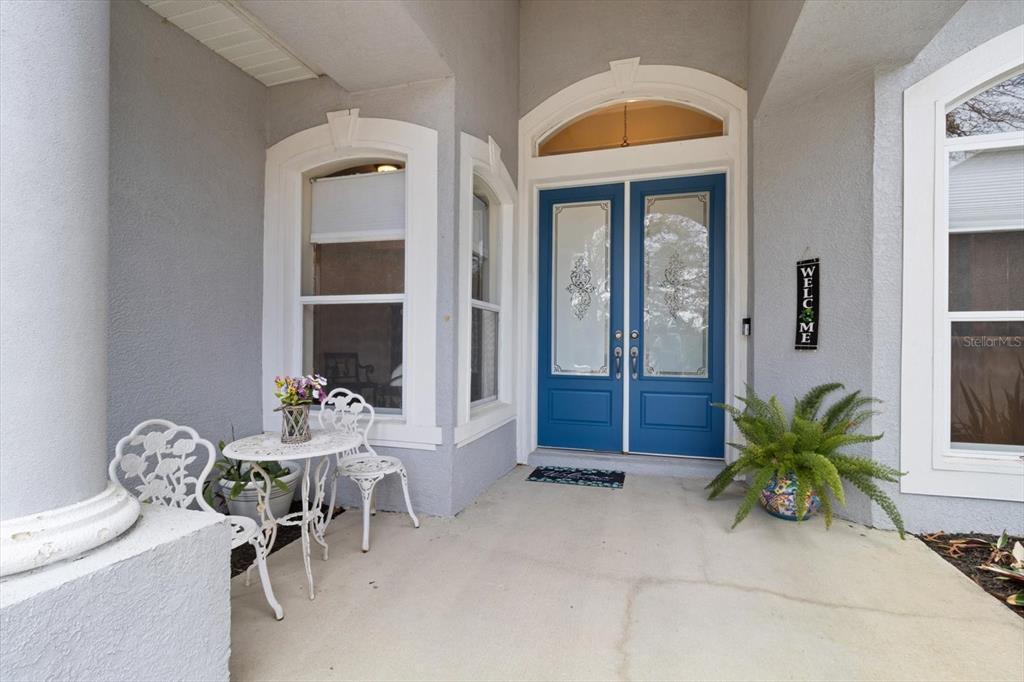 A covered front porch features a blue double door, white bistro set, and potted fern — 5194 W DEPUTY DRIVE, BEVERLY HILLS, FL