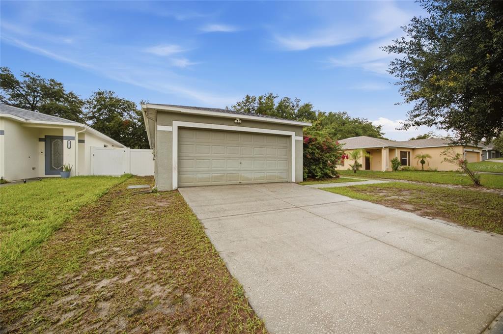 A single-story house exterior features a beige garage, a concrete driveway, and a grassy lawn — 13708 TRAMORE DRIVE, ODESSA, FL