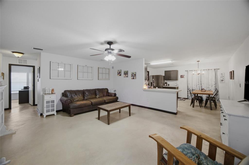 A living room with a brown leather sofa, coffee table, and an open-concept kitchen area — 13708 TRAMORE DRIVE, ODESSA, FL