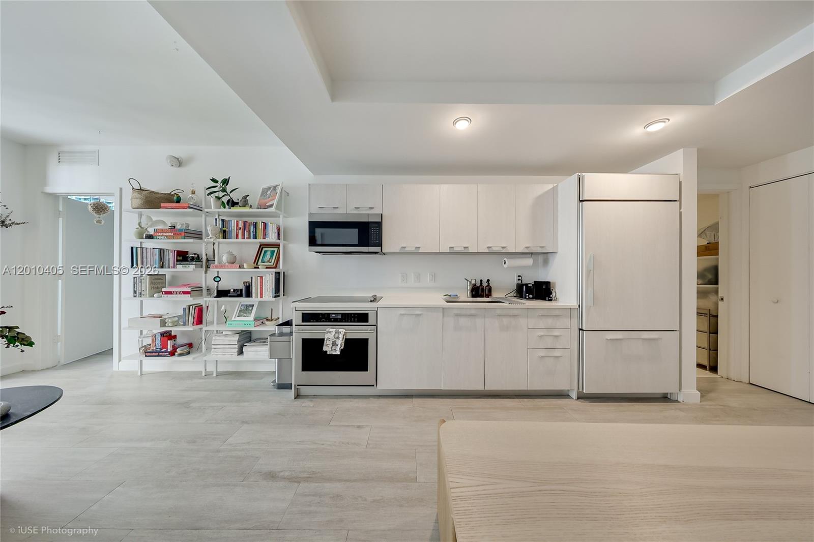 A modern kitchen features white cabinetry, stainless steel appliances, and an adjacent open shelving unit — 55 SW 9th St # 2109, Miami FL 33130, MIAMI, FL