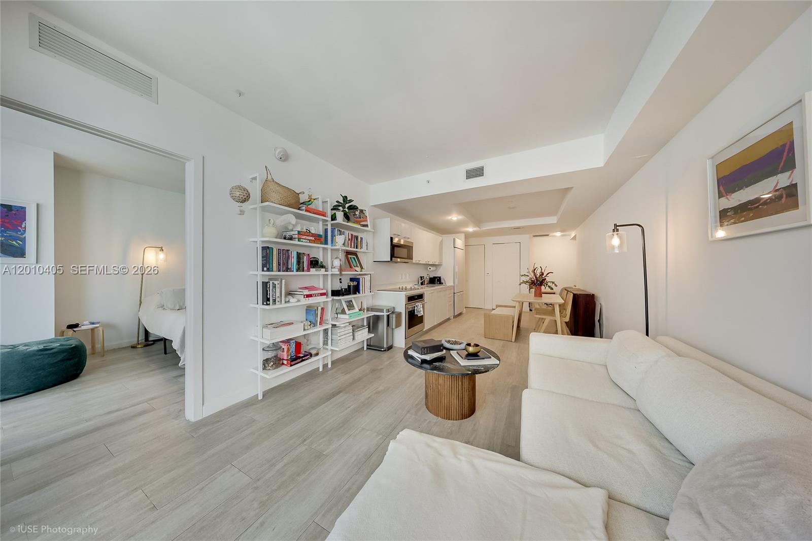 A modern, open-concept living room and kitchen area with light wood flooring and white walls — 55 SW 9th St # 2109, Miami FL 33130, MIAMI, FL