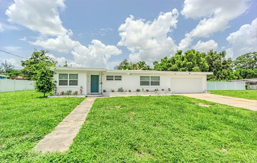 A single-story white house with a teal front door, a garage, and a large lawn — 8706 RUTH PLACE, TAMPA, FL