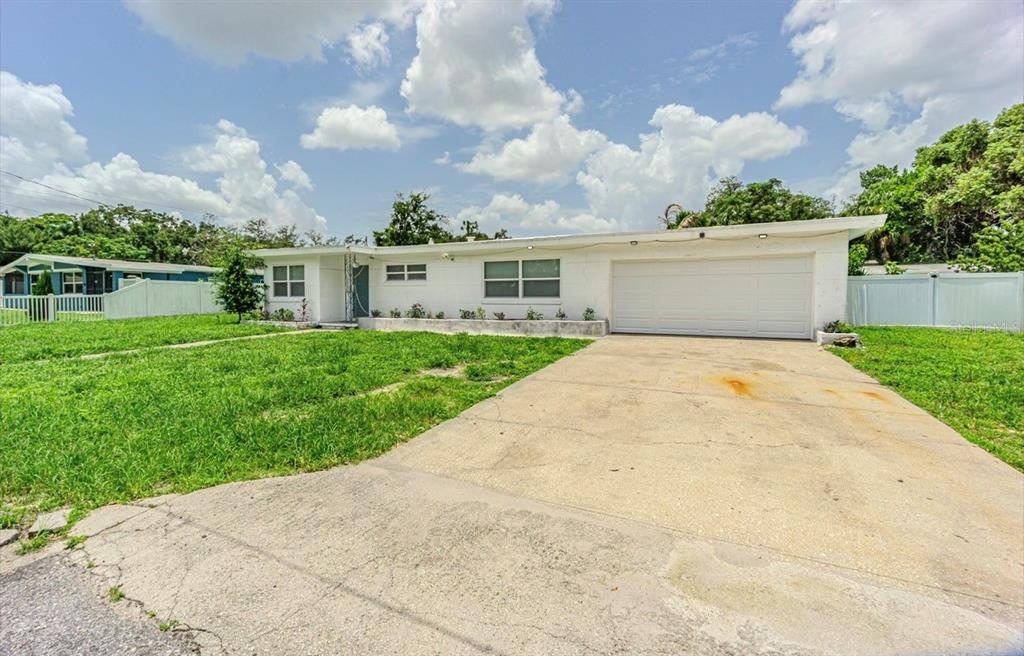 A single-story white house with a concrete driveway and a two-car garage — 8706 RUTH PLACE, TAMPA, FL