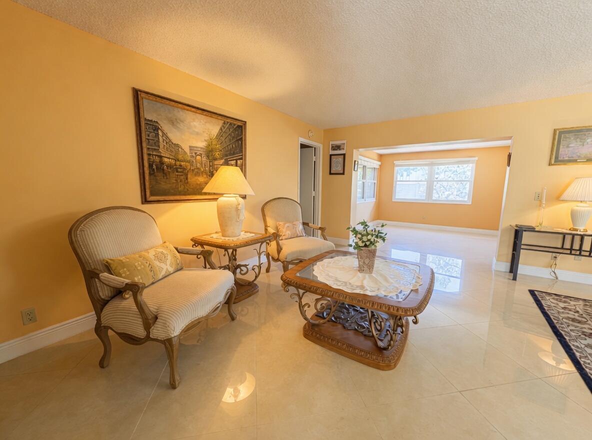 A living room features light-colored tile floors, two upholstered armchairs, and a decorative coffee table — 6304 Emerald Sky Lane, FL 33463, FL