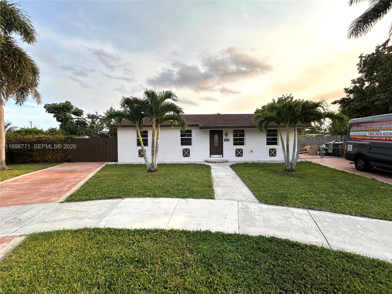 A single-story white house with a brown roof, two palm trees, and a concrete walkway — 1666 SW 3rd Ct, Homestead FL 33030, HOMESTEAD, FL