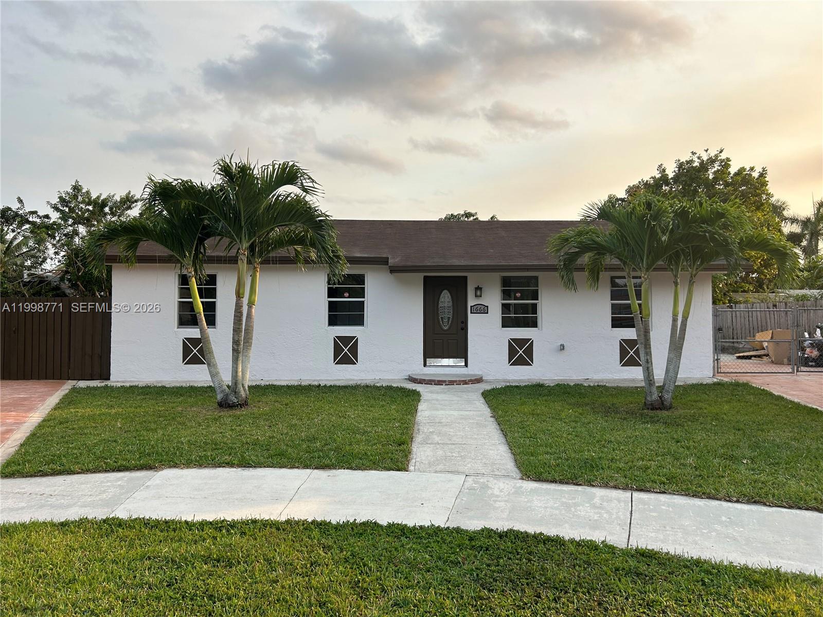 A single-story white house with a brown roof, two palm trees, and a front walkway — 1666 SW 3rd Ct, Homestead FL 33030, HOMESTEAD, FL