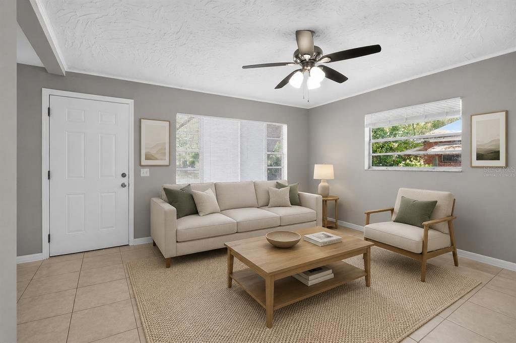 A living room with a beige sofa, armchair, coffee table, and ceiling fan on tile floors — 2209 9TH COURT NE, WINTER HAVEN, FL