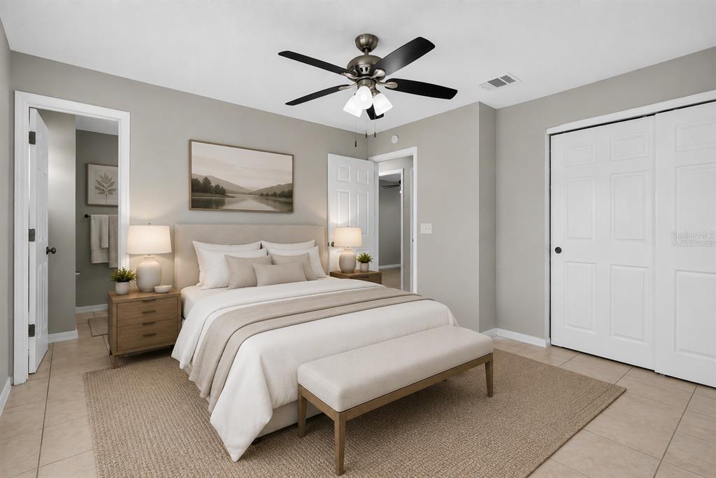 A bedroom features a bed with neutral bedding, a ceiling fan, and a beige area rug — 2209 9TH COURT NE, WINTER HAVEN, FL