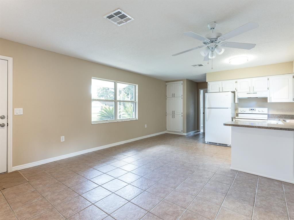 An open-concept kitchen and living area with tile flooring, white cabinets, and a ceiling fan — 1314 CR 443, LAKE PANASOFFKEE, FL