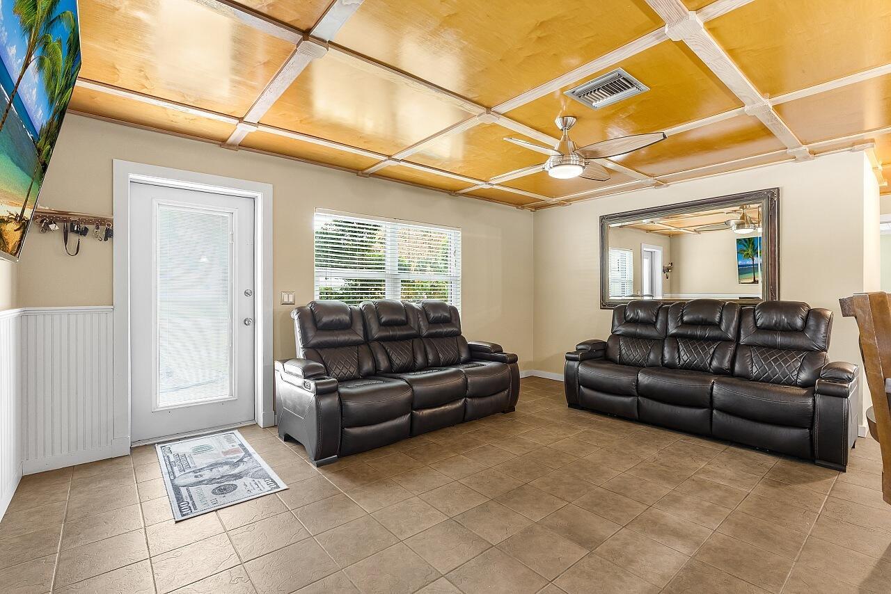 A living room features two dark leather sofas, tile flooring, and a coffered wood ceiling — 266 20th Avenue, Vero Beach FL 32962, VERO BEACH, FL
