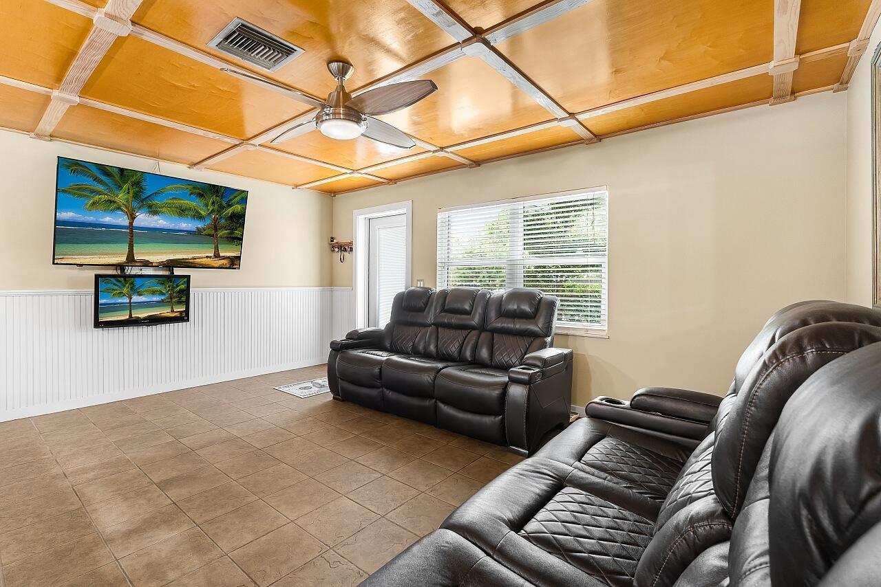 A living room features a coffered wood ceiling, tile flooring, and two wall-mounted televisions — 266 20th Avenue, Vero Beach FL 32962, VERO BEACH, FL