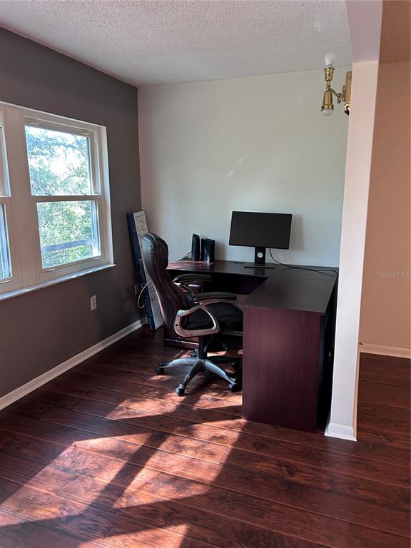A home office features dark wood flooring, a corner desk, and a window with natural light — 150 EL DORADO UNIT 208, WINTER HAVEN, FL
