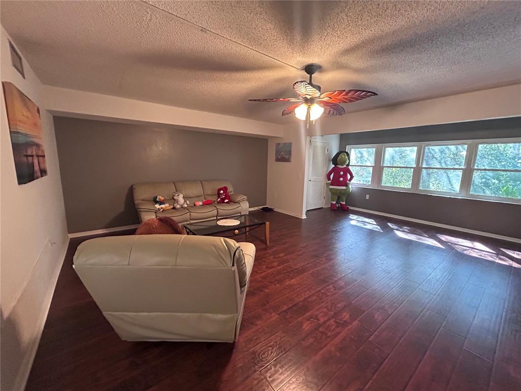 A living room features dark wood-look flooring, a ceiling fan, and a light-colored sofa — 150 EL DORADO UNIT 208, WINTER HAVEN, FL
