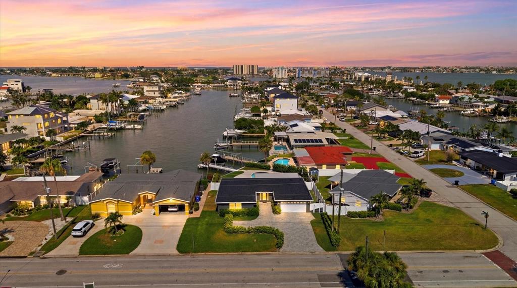An aerial view shows waterfront houses with boat docks along a canal at sunset — 121 79TH STREET S, ST PETERSBURG, FL