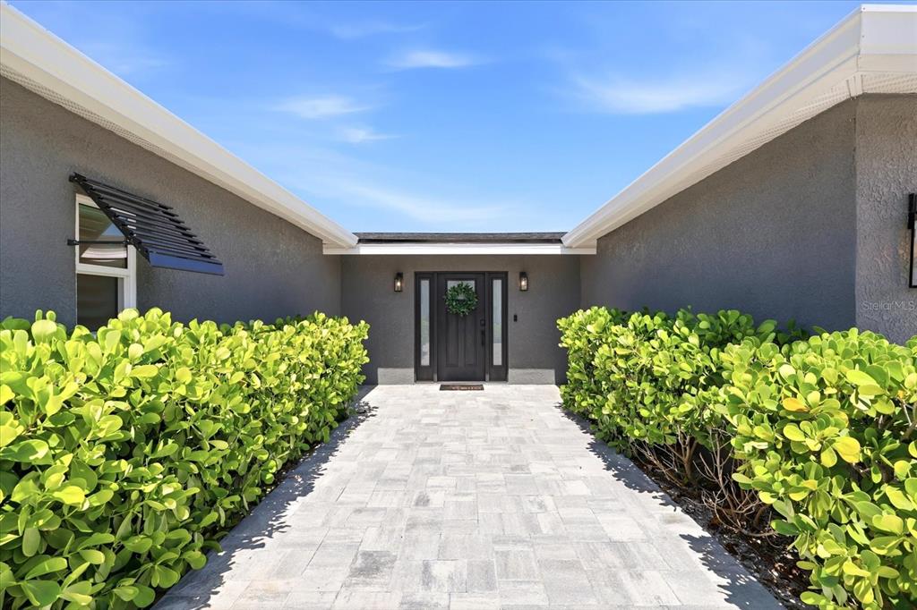 A stone walkway leads to a dark front door flanked by large green hedges — 121 79TH STREET S, ST PETERSBURG, FL