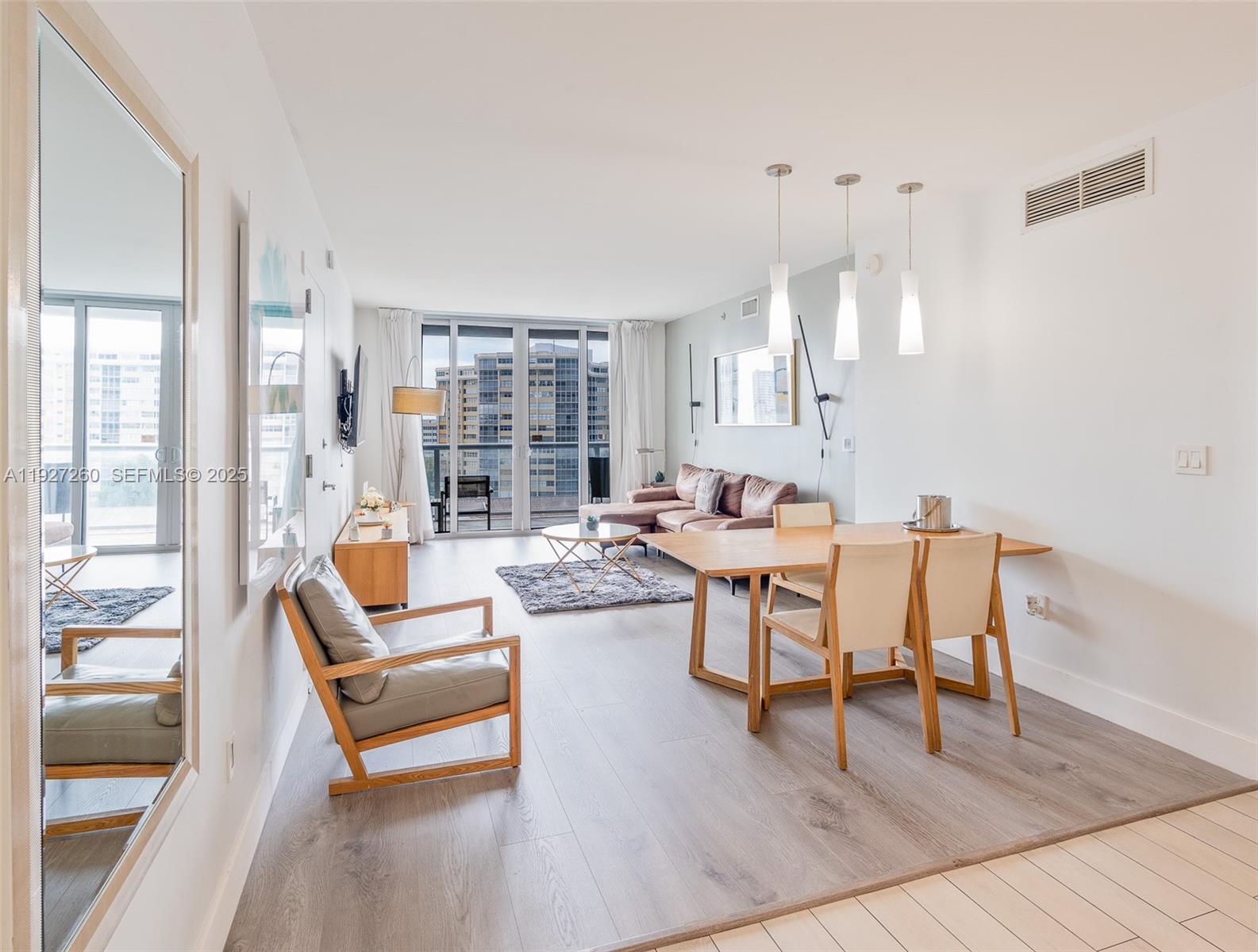 A modern open-concept living and dining area features light wood flooring and floor-to-ceiling windows — 2602 E Hallandale Beach Blvd # R809, Hallandale Beach FL 33009, HALLANDALE BEACH, FL