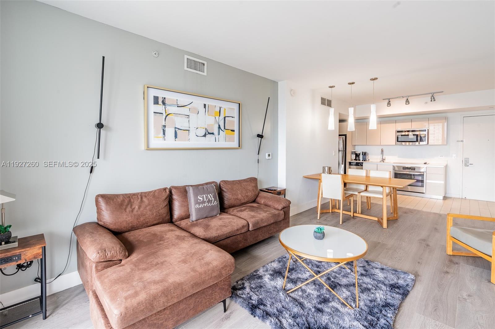 A living room features a brown sectional sofa, a coffee table, and an open kitchen — 2602 E Hallandale Beach Blvd # R809, Hallandale Beach FL 33009, HALLANDALE BEACH, FL