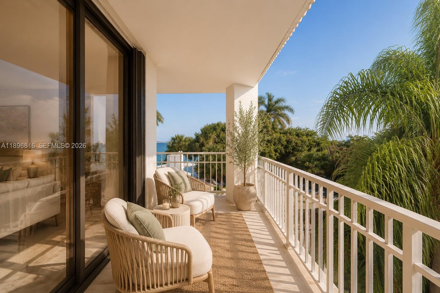 A balcony features two wicker chairs, a small table, and a view of palm trees — 4000 Towerside Ter # 402, Miami FL 33138, MIAMI, FL