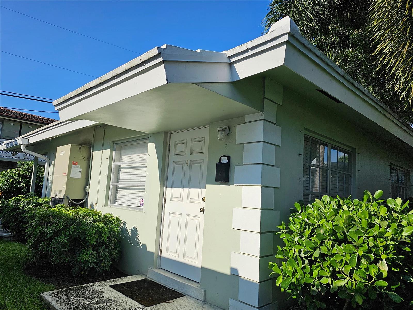 A light green exterior wall features a white front door, windows, and decorative corner blocks — 2120 NE 41st Street # D, Lighthouse Point FL 33064, LIGHTHOUSE POINT, FL