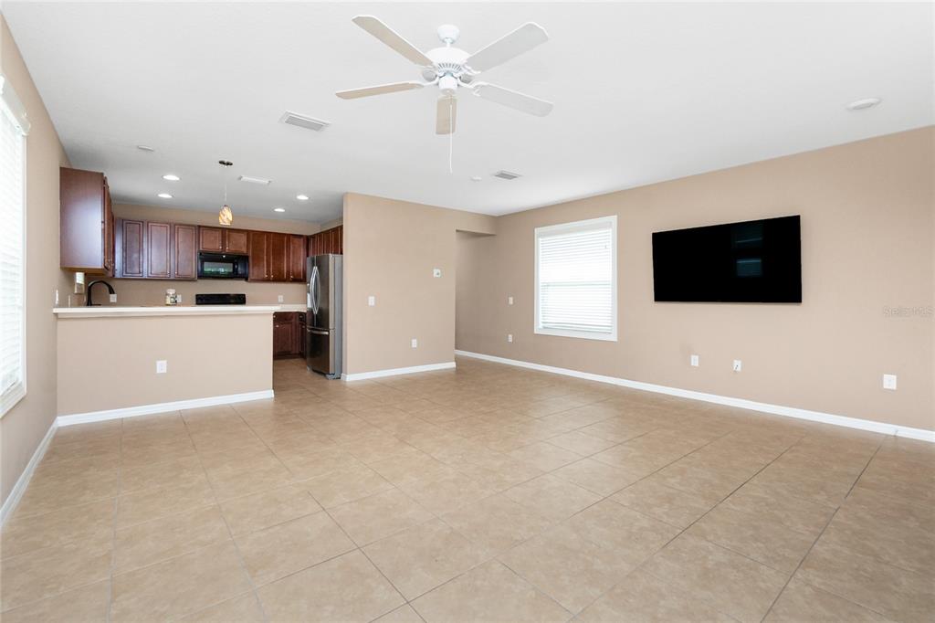 An open-concept living room features tile flooring, a ceiling fan, and an adjacent kitchen area — 12753 SAGEWOOD DRIVE, VENICE, FL