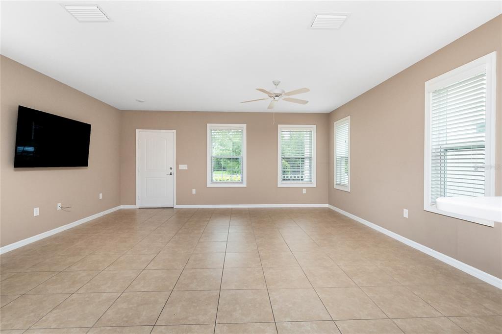 A spacious living room features beige walls, tile flooring, a ceiling fan, and several windows — 12753 SAGEWOOD DRIVE, VENICE, FL