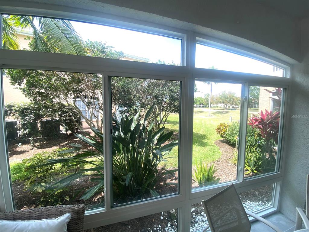 A sunroom features large windows overlooking a grassy yard with trees and landscaping — 801 GONDOLA PARK DRIVE UNIT 801, VENICE, FL