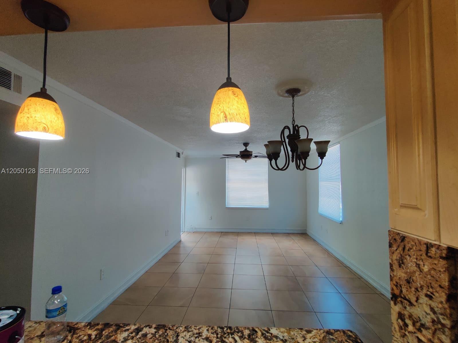 A dining area features tile flooring, two pendant lights, a chandelier, and a ceiling fan — 5705 W 20th Ave # 215, Hialeah FL 33012, HIALEAH, FL