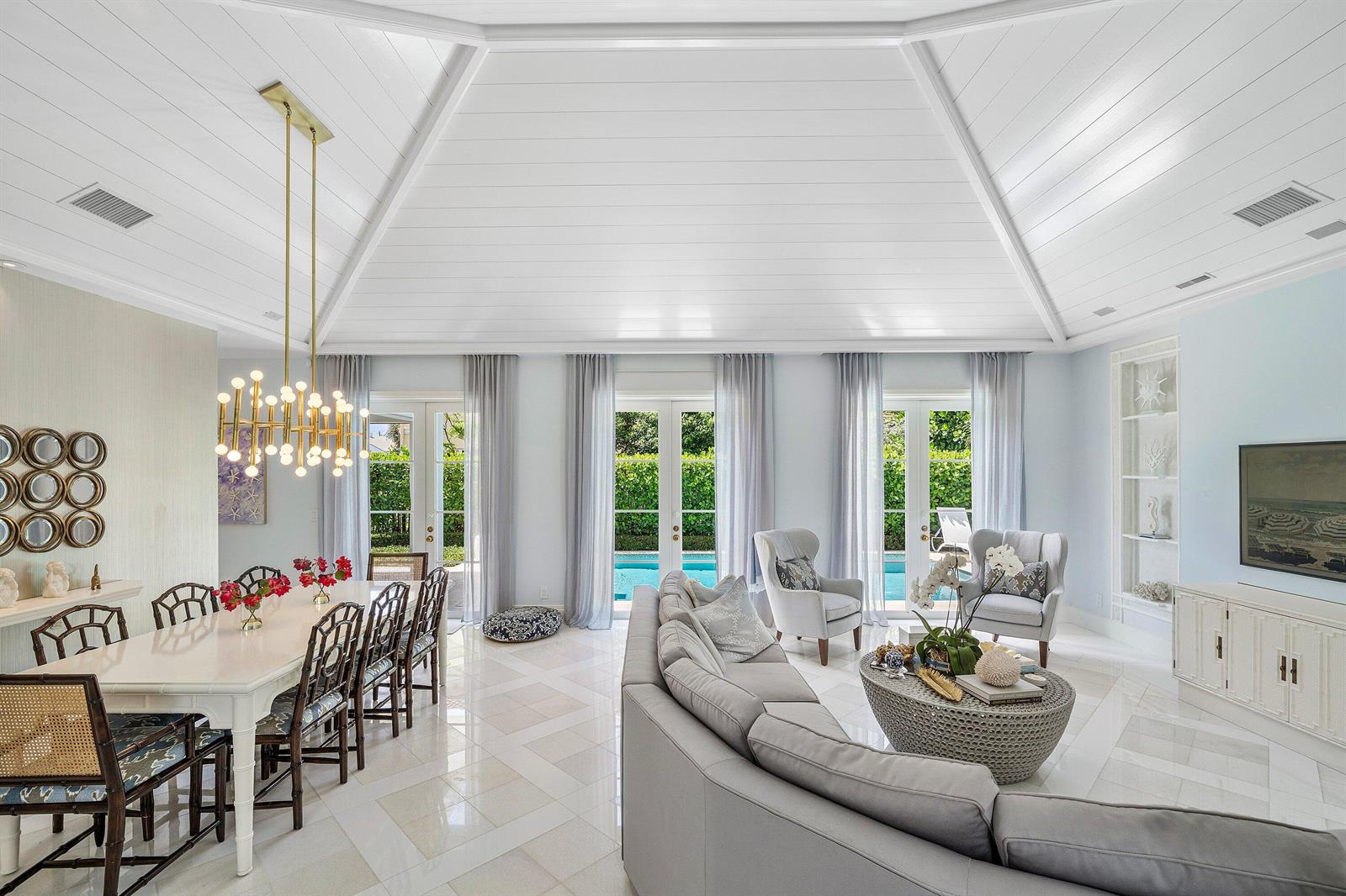 A bright living and dining area with a vaulted ceiling, tile floors, and pool views — 106 Beachway Drive, Ocean Ridge FL 33435, OCEAN RIDGE, FL