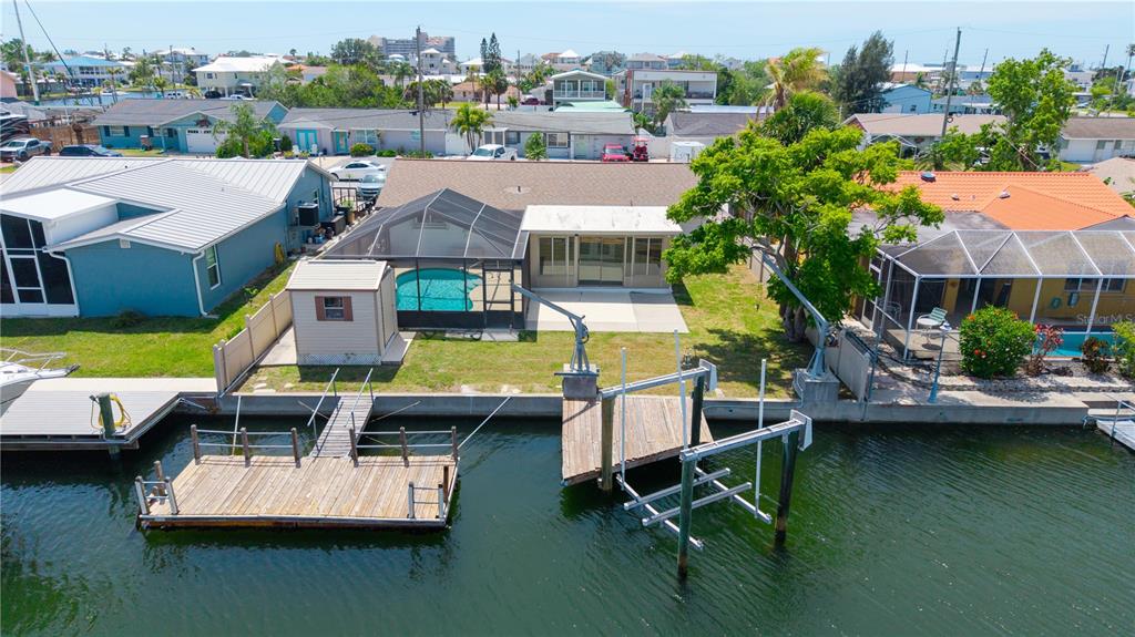 An aerial view of a waterfront house with a pool, dock, and boat lift — 13912 DARLENE AVENUE, HUDSON, FL