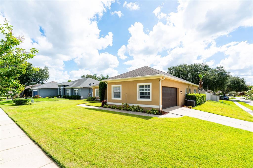 A tan single-story house with a brown roof and garage sits on a corner lot — 1643 SHONNORA DRIVE, GOTHA, FL