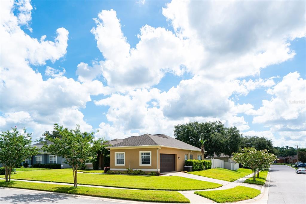 A single-story house with a tan stucco exterior and a green lawn at sunset — 1643 SHONNORA DRIVE, GOTHA, FL