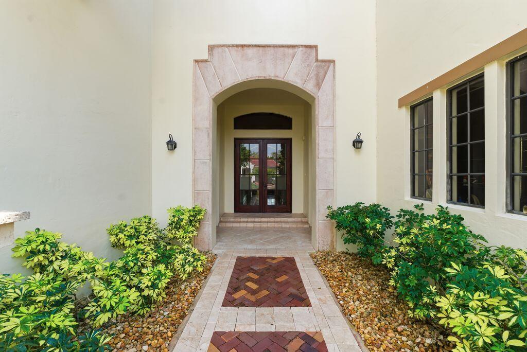 A paved walkway leads to a recessed front entrance with double doors and stone archway — 9460 Eden Manor, Parkland FL 33076, PARKLAND, FL