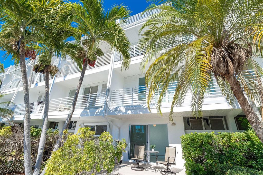 A white multi-story apartment building with balconies, palm trees, and a ground-level patio area — 8226 HARBORSIDE CIRCLE, ENGLEWOOD, FL