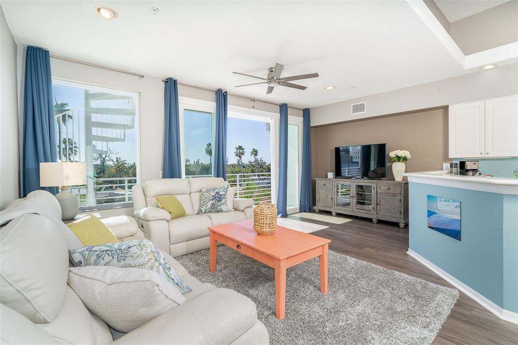 A living room with white leather sofas, an orange coffee table, and a balcony view — 8226 HARBORSIDE CIRCLE, ENGLEWOOD, FL