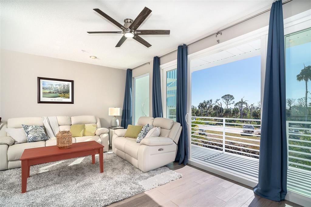 A living room features white leather sofas, a red coffee table, and a balcony view — 8226 HARBORSIDE CIRCLE, ENGLEWOOD, FL