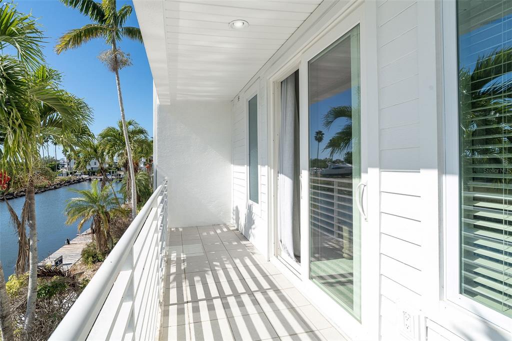 A balcony with white railings overlooks a canal lined with palm trees — 8226 HARBORSIDE CIRCLE, ENGLEWOOD, FL
