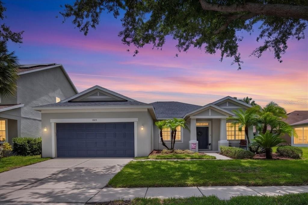 A single-story house with a gray garage, light-colored exterior, and a landscaped front yard — 11023 HOLLY CONE DRIVE, RIVERVIEW, FL