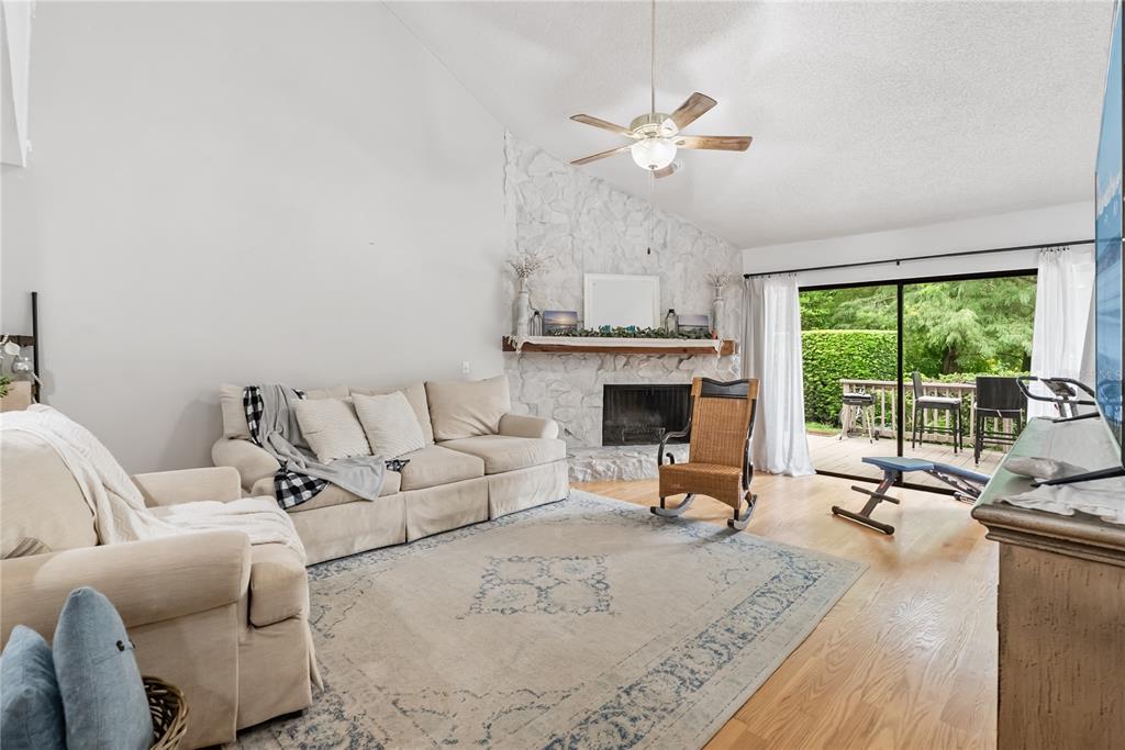 A living room features a white stone fireplace, beige sofa, rocking chair, and sliding glass doors — 303 OLD MILL POND ROAD UNIT 303, PALM HARBOR, FL