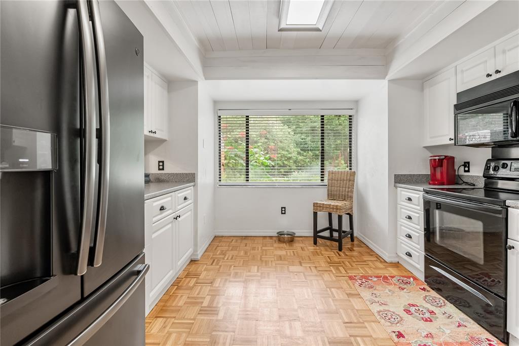 A kitchen features white cabinets, stainless steel appliances, a parquet floor, and a large window — 303 OLD MILL POND ROAD UNIT 303, PALM HARBOR, FL