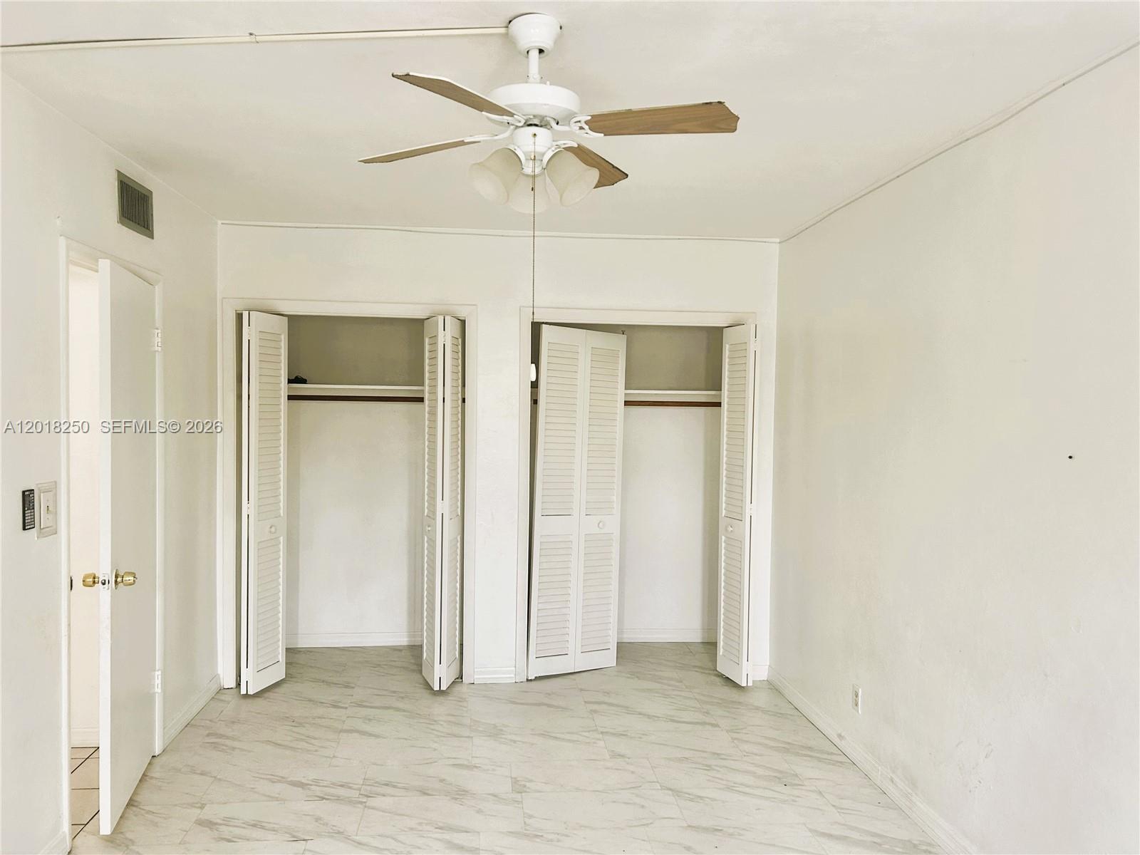 A bedroom features a wooden bed frame, white bedding, light wood furniture, and marble flooring — 1958 Monroe St # 209, Hollywood FL 33020, HOLLYWOOD, FL