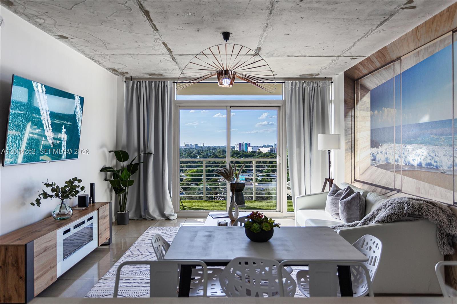 A modern living and dining area features a concrete ceiling, large windows, and balcony views — 3250 NE 1st Ave # 913, Miami FL 33137, MIAMI, FL