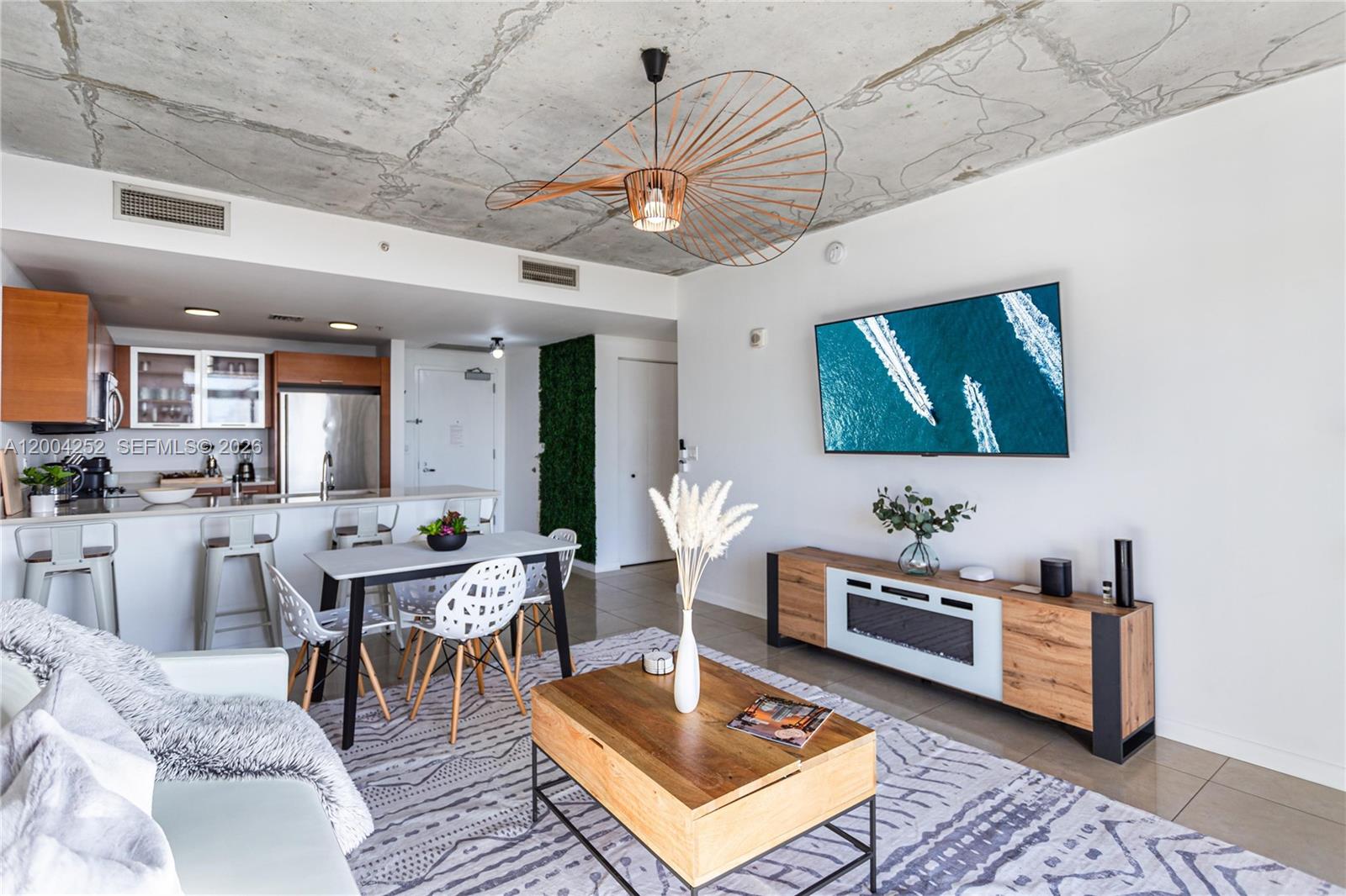 A modern living room features a concrete ceiling, a dining area, and a television console — 3250 NE 1st Ave # 913, Miami FL 33137, MIAMI, FL