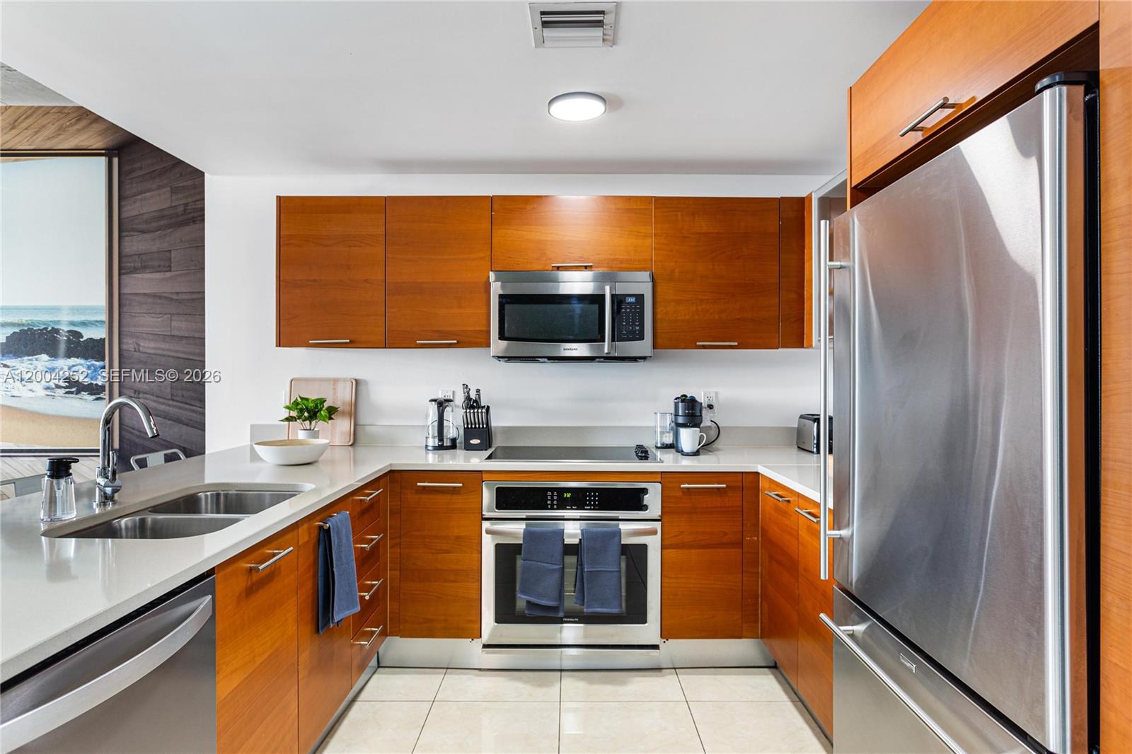 A modern kitchen features wood cabinets, stainless steel appliances, and light-colored countertops — 3250 NE 1st Ave # 913, Miami FL 33137, MIAMI, FL